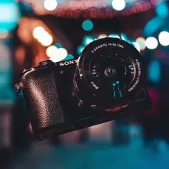 Aparat Sony z obiektywem na tle kolorowych świateł.