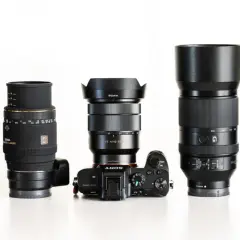 Pięć obiektywów fotograficznych i aparat Sony Alpha ustawione w rzędzie na białym tle.