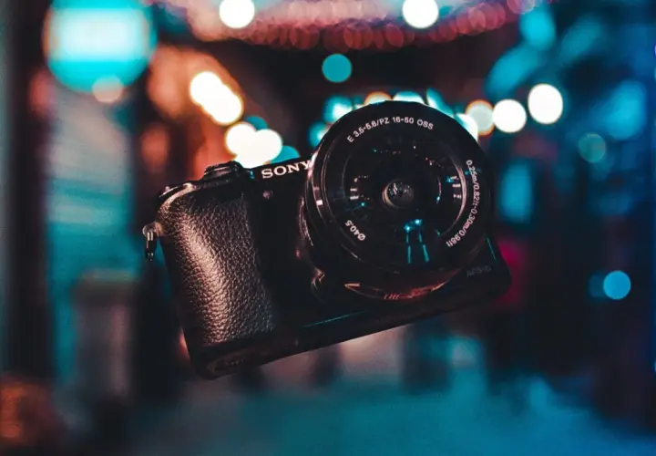 Aparat Sony z obiektywem na tle kolorowych świateł.