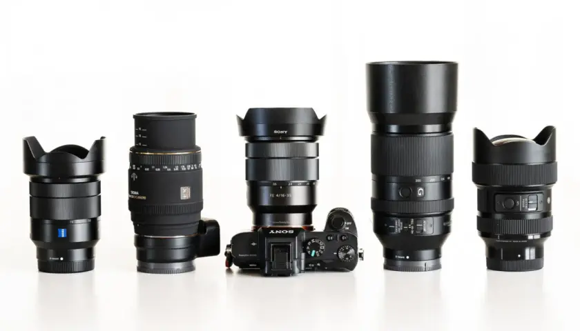 Pięć obiektywów fotograficznych i aparat Sony Alpha ustawione w rzędzie na białym tle.