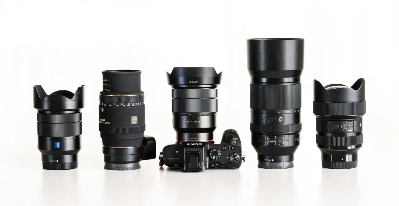 Pięć obiektywów fotograficznych i aparat Sony Alpha ustawione w rzędzie na białym tle.